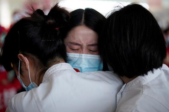 Personal sanitario se abraza en el aeropuerto internacional de Wuhan. Foto: Reuters.